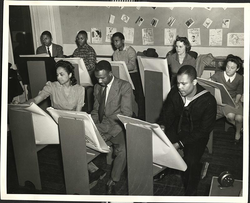 Room of adults drawing on large paper tablets supported by easels.