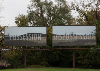 Two billboards of a grassy hills with words "Possession" and "Dispossession"