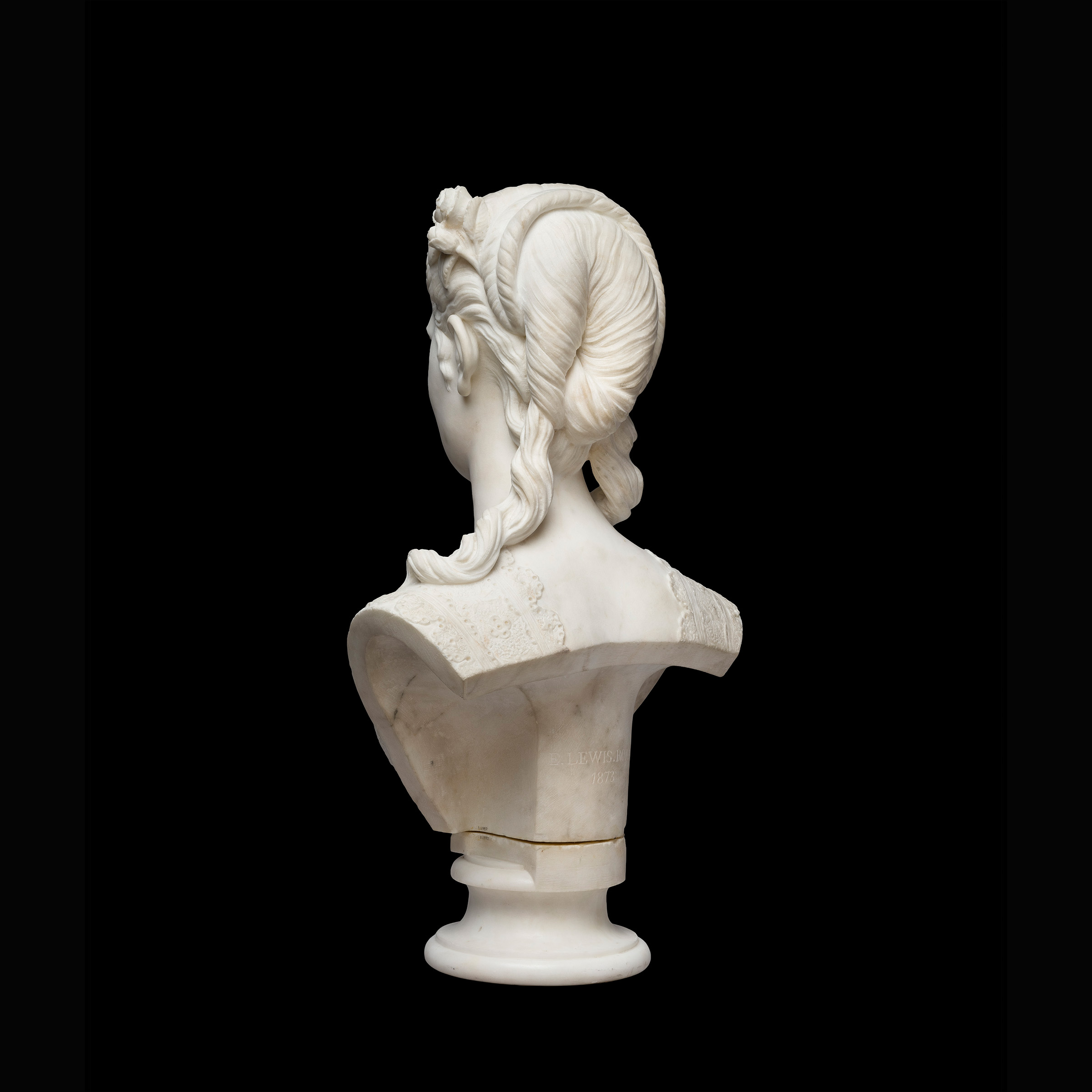 Back view of a marble statue depicting a woman from the shoulders up, with a 19th century hairstyle.