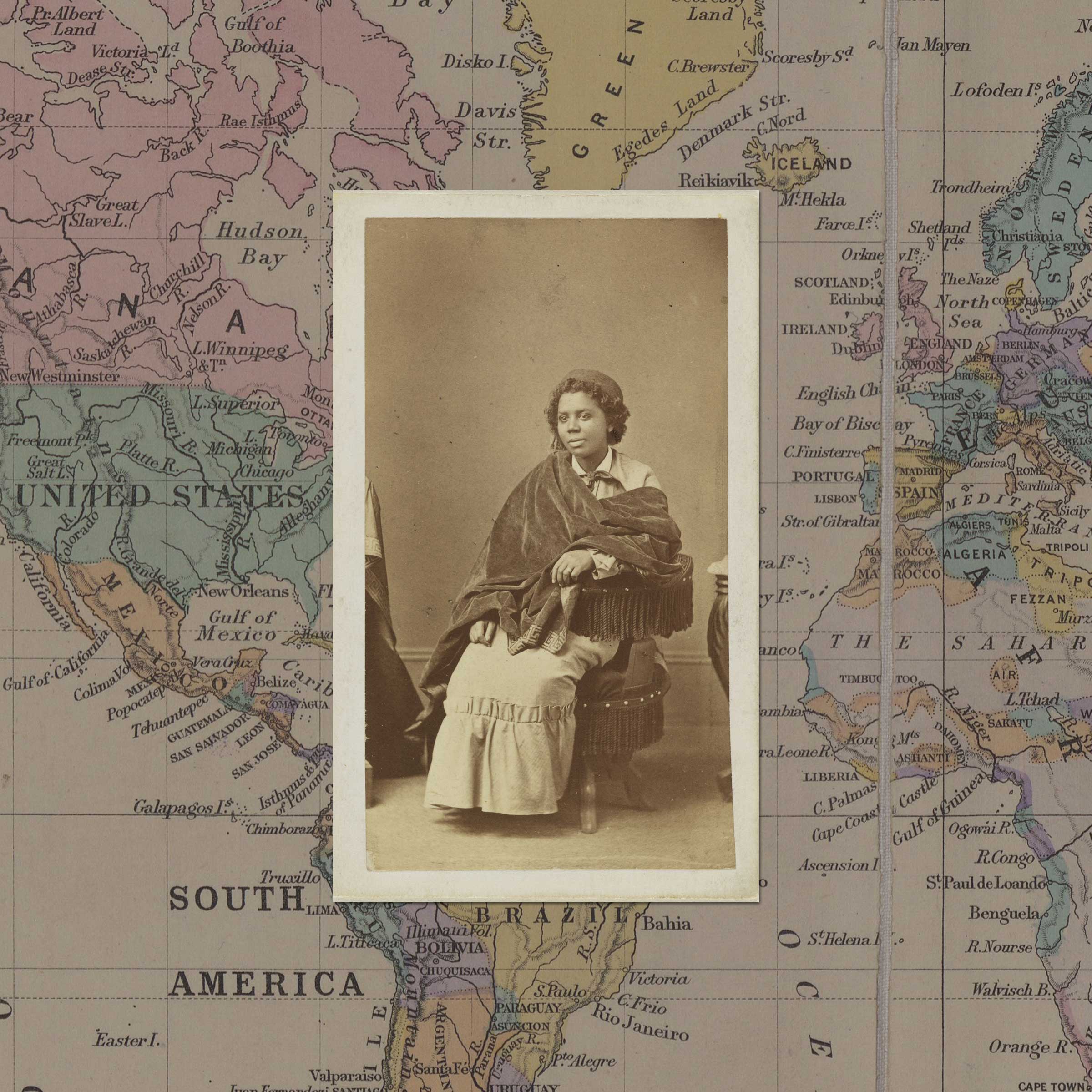Archival photograph of seated Black woman, facing the camera, with a background made of a 19th-century map.