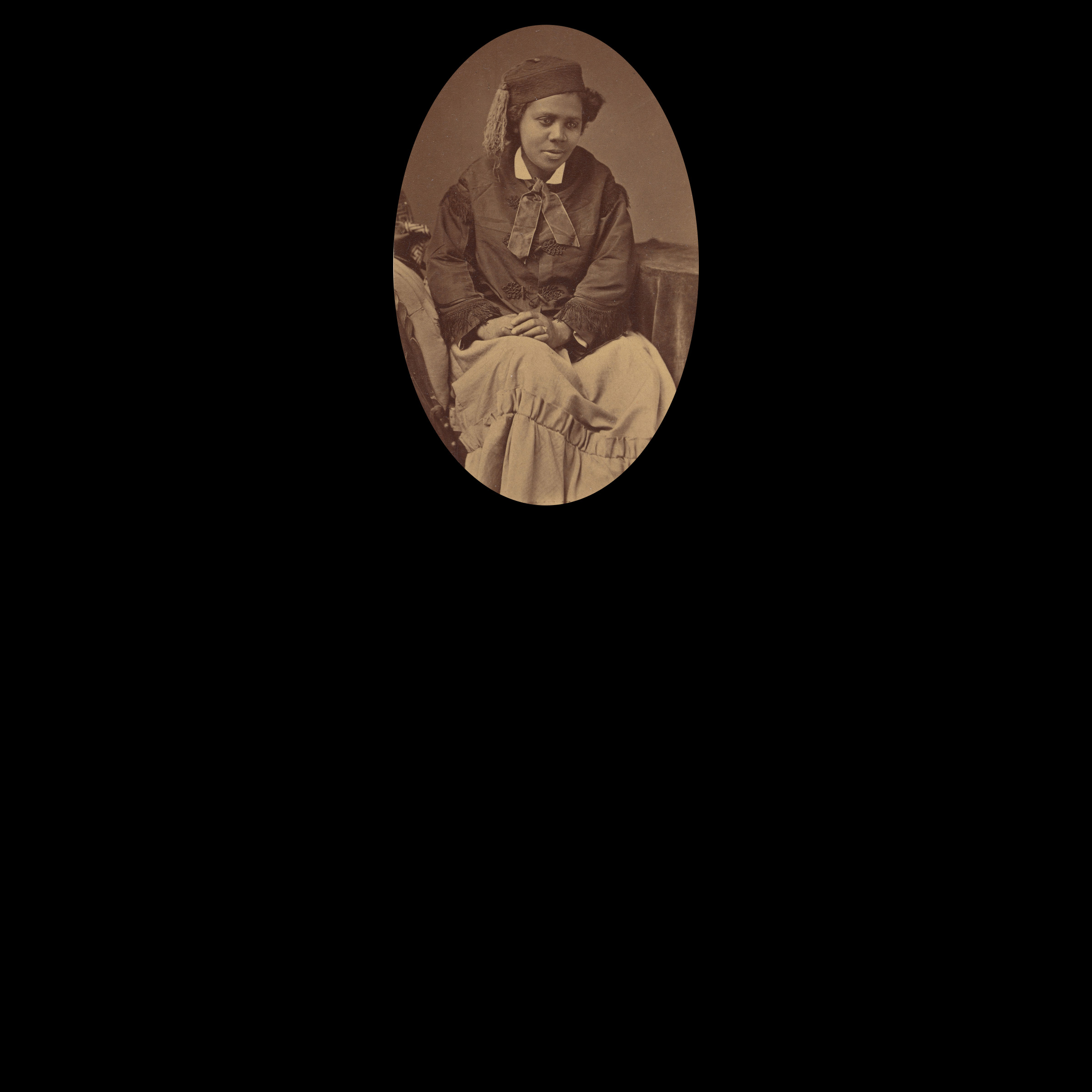 Oval crop of archival photograph of Black woman seated, facing the camera, with a black background.